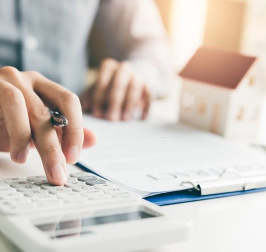 Home agents are using a calculator to calculate the loan period each month for the customer.