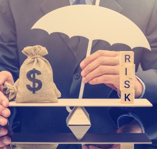 Financial risk assessment / portfolio risk management and protection concept : Businessman holds a white umbrella, protects a dollar bag on basic balance scale, defends money from being cheat or fraud