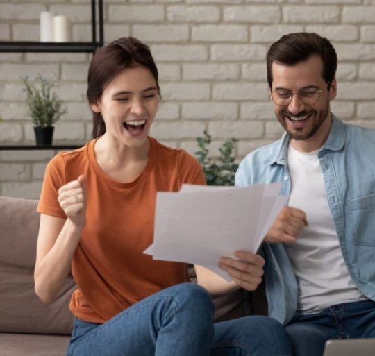 Excited young Caucasian man and woman spouses triumph get good pleasant news in postal letter correspondence, overjoyed millennial couple tenants or renters celebrate bank notice approval